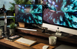 Two computer screens sitting on a wooden desk